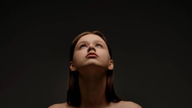 Bir kadın portresi canlı, koyu bir arka plana bakarak zarafet ve içgözlem yakalıyor..