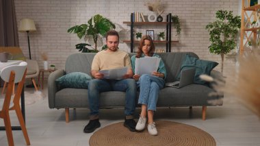 Bir çift bir kanepede dizüstü bilgisayarla oturuyor, online alışveriş yapıyorlar. Odaklanmışlar ve kredi kartı kullanıyorlar..