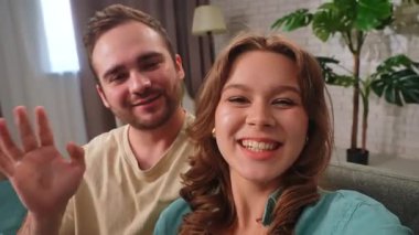 Gülümseyen bir çift rahat bir dekor ve yemyeşil bir bitki ile çevrili kanepede rahat bir anın tadını çıkarır..