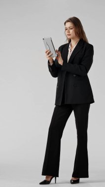 Tabletli siyah takım elbiseli bir kadın iş ortamında profesyonellik ve güven yayıyor. beyaz arkaplanda izole