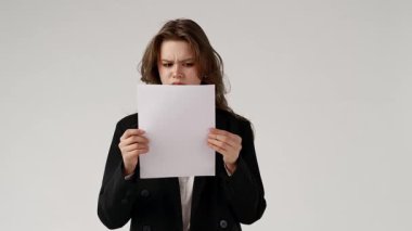 Takım elbiseli bir kadın, bir belgeyi şaşkınlık bakışlarıyla inceliyor ve içeriğini anlamaya çalışıyor. beyaz arkaplanda izole