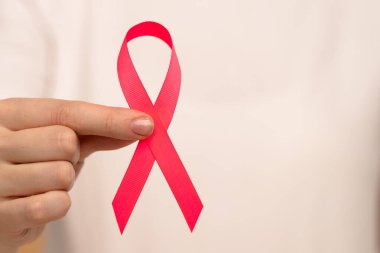 Pembe bir kurdele tutan bir el sağlık sorunları ve kampanyalara verilen bilinci ve desteği sembolize ediyor. Göğüs kanseri farkındalık günü konsepti.