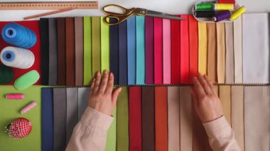 Giysi dikmek için iplik seçen tasarımcıların üst görüntüsü. Renkli bir dikiş malzemesi koleksiyonu kumaş, iplik, makas ve cetvel, dikiş işi için mükemmel..