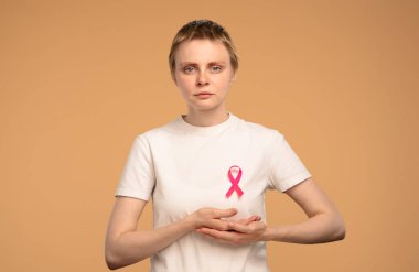 Bir kadın, göğüs kanseri farkındalığını, sağlığı ve desteği simgeleyen pembe bir kurdele takıyor. Göğüs kanseri farkındalık günü konsepti.