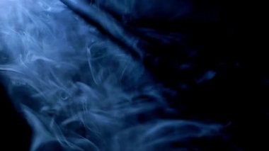 Yumuşak mavi dumanın soyut görüntüsü karanlık bir arkaplanda yavaşça kıvrılarak gizemli ve atmosferik bir görsel etki yaratıyor..