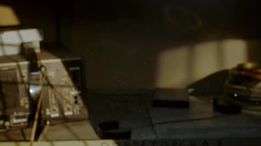 Eski bir film düzenleme odasında sıcak güneş ışığıyla aydınlatılan yüzen toz, retro ekipman, makaralar ve nostaljik atmosfer..