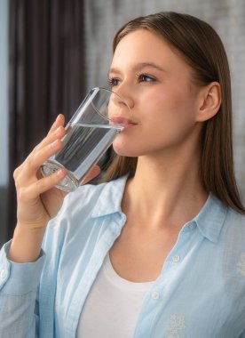 Bir bardak temiz su içen bir insan, hidrasyon ve sağlık yararlarını teşvik eder. Refah temaları için ideal.