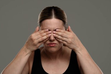 Siyah tişörtlü bir kadın göz ağrısı ya da rahatsızlık hissederken elleriyle gözlerini kapatır. Sağlık, tedavi ve ağrı yönetimi kavramı.