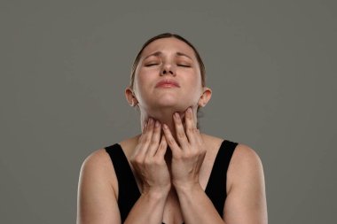 Bir kadın boğazını tutarken gözle görülür bir rahatsızlık hisseder. Boğaz ağrısı ya da tahriş olabilir. Sağlık, tedavi ve ağrı kesici kavramı.