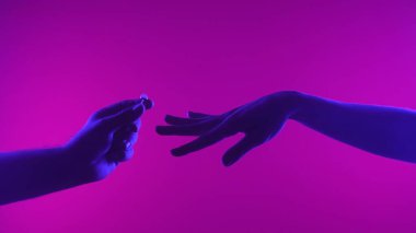 Bir el, sanatsal bir ortamda romantik bir teklifi sembolize eden neon ışıklı bir yüzük sunar..