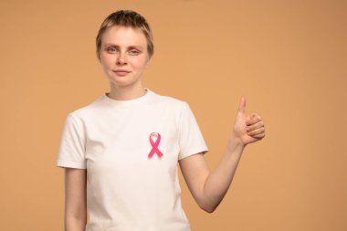 Göğüs kanserine karşı verilen mücadeleyi sembolize eden pembe kurdeleli beyaz gömlek giyen bir kadın iyi niyet göstergesi. Göğüs kanseri farkındalığı günü konsepti.