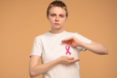 Beyaz gömlekli bir kadın pembe bir kurdele tutuyor. Meme kanseri farkındalığını ve amacını simgeliyor. Göğüs kanseri farkındalık günü konsepti.