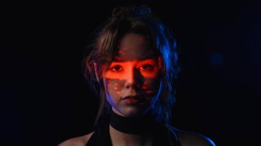 Yüzünde kırmızı çizgili bir desen olan dramatik bir kadın portresi gergin ve gizemli bir atmosfer yaratıyor..