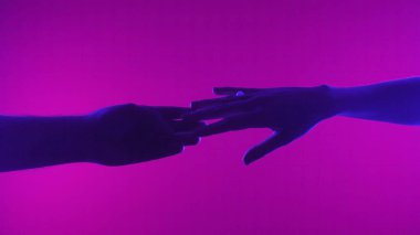 İki elin siluetleri birbirine nazikçe uzanıyor parlak pembe bir arka plana doğru, bağlantıyı sembolize ediyor..