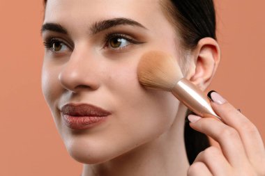 Yanaklarında fırçayla makyaj yapan bir kadının yakın plan görüntüsü pürüzsüz bir ten ve belirli özellikler için.