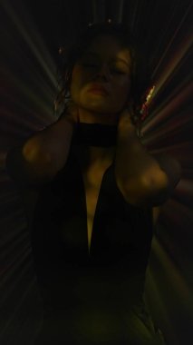 Siyah kıyafetli bir kadının sanatsal portresi radyal projektör ışık deseninin önünde duruyor ve gizemli ve sinematik bir görsel efekt yaratıyor..