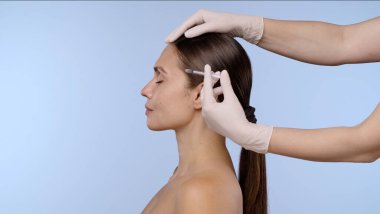 Yüz hatlarını geliştirmek, cilt bakımını ve estetik gelişim tekniklerini göstermek için deri enjeksiyonu alan bir kadın..