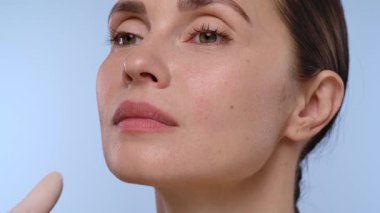 Bir kadın, çenesine eldiven takmış profesyonel bir el tarafından estetik iğne vurulur. Bu da tıbbi estetik prosedürü yakından temsil eder.