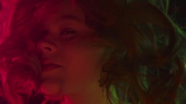 Renkli ya da yansıtıcı camdan görüntülenen bir kızın yakın portresi, sinematik, gerçeküstü bir etki için kırmızı, yeşil ve altın ışıkla aydınlatılır..