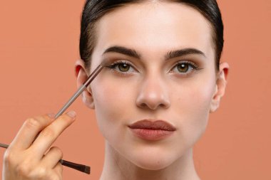 Bir kadın ustalıkla makyaj yapar, doğal güzelliği detaylara ve hassasiyete dikkat ederek vurgular..