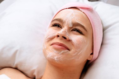 Baloncuk temizleyici yüz maskesi derisini örterken genç bir kadın huzur içinde yatıyor. Güzellik ve güzellik salonları için içerik, promosyon güzellik ürünleri.