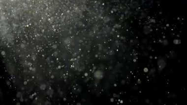 Yumuşak beyaz toz parçacıkları karanlık bir boşlukta asılı, ışıkla aydınlatılıyor. Soyut arka planlar için mükemmel ruhani ve rüya gibi bir atmosfer..