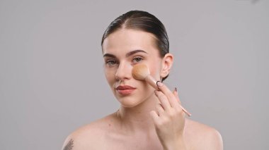 Bir kadın makyajını yumuşak bir fırçayla yapar, doğal güzelliğini arttırır ve kusursuz bir görünüş elde eder..