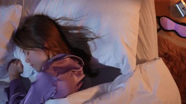 Genç bir kadının geceleri yatakta yatıp uyumaya çalışmasının en güzel görüntüsü. Komodindeki lamba ve uyumak için gerekli eşyalar uykusuzluk atmosferini vurgular..