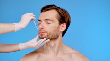 Yüz hatlarını geliştirmek, cilt bakımını ve estetik gelişim tekniklerini göstermek için deri enjeksiyonu alan bir adam..