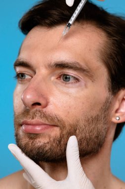 Yüz hatlarını geliştirmek, cilt bakımını ve estetik gelişim tekniklerini göstermek için deri enjeksiyonu alan bir adam..