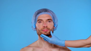 Bir adam kozmetik bir prosedüre hazırdır. Başlık takar ve yönlendirme için yüzünde işaretler olur. Erkekler için estetik ameliyatlar, estetik cerrahi ve cilt bakımı ile ilgili içerik için ideal.