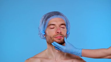 Bir adam kozmetik bir prosedüre hazırdır. Başlık takar ve yönlendirme için yüzünde işaretler olur. Erkekler için estetik ameliyatlar, estetik cerrahi ve cilt bakımı ile ilgili içerik için ideal.