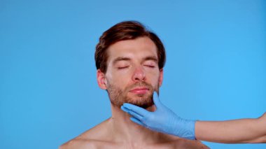 Bir adam estetik ameliyata hazırdır. Yüzünde işaretler vardır. Erkekler için estetik ameliyatlar, estetik cerrahi ve cilt bakımı ile ilgili içerik için ideal.