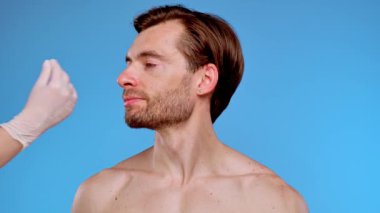 Yüz hatlarını geliştirmek, cilt bakımını ve estetik gelişim tekniklerini göstermek için deri enjeksiyonu alan bir adam..