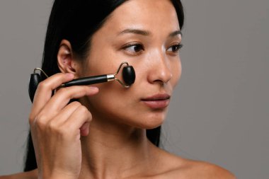 Bir kadın, cilt bakımını arttırmak ve deri görünümünü iyileştirmek için yüzüne yeşim taşı takıyor..