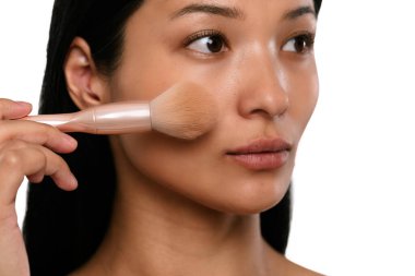 Bir kadın fırça kullanarak makyaj yapar, pürüzsüz ve kusursuz bir ten elde eder..