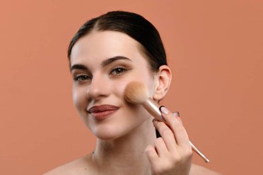 Bir kadın kusursuz bir görünüm elde etmek için makyajını fırçayla yapar. Görüntü güzelliği ve zarafeti yakalar..