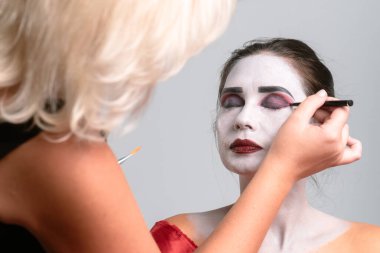 Bir makyaj sanatçısı, detaylara odaklanarak, tiyatro veya kostüm amacıyla cesur yüz boyası ve makyaj uygular..