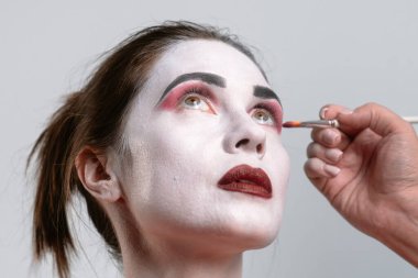 Çarpıcı bir yüz boyama süreci canlı renkler ve hassas fırça darbeleri ile dramatik özellikleri vurguluyor..