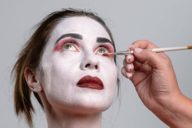 Beyaz yüz boyası ve koyu kırmızı ruj sürmüş bir kadının yakın plan fotoğrafı..