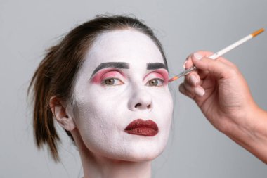 Bir insan çarpıcı bir sanatsal etki için beyaz makyajla ve kalın renklerle değiştiriliyor..