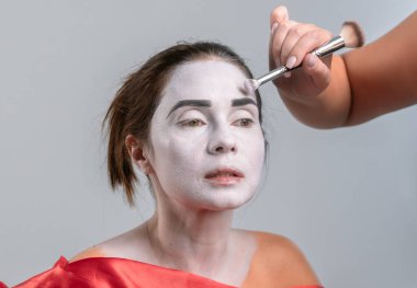 Yakından çekilen fotoğrafta siyah kaşlarını beyaza boyayan bir insan yüzü görülüyor. Dramatik makyajı vurguluyor..