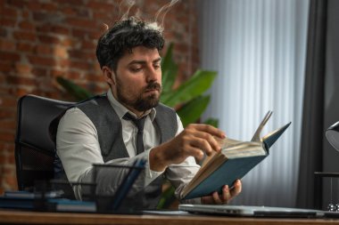 Bir adam kafasından duman çıkan, yoğun düşünceyi sembolize eden bir kitap okumaya derinden dalmıştır..