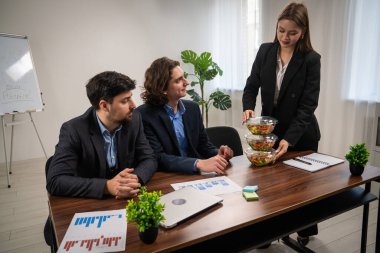Ekip üyelerinin üretkenliği artırmak için sağlıklı yemek seçeneklerini araştırdıkları profesyonel bir iş toplantısı..