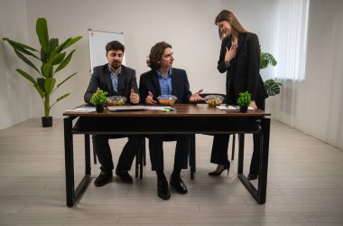 Üç meslektaş, modern ofis ortamında bir konferans masasında profesyonel bir tartışmaya girişti..