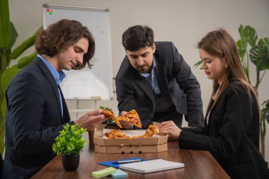 Modern ofis ortamında bir toplantı sırasında bir iş ekibi pizzanın tadını çıkarmak için ara verir..