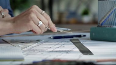 Bir birey, masanın üzerinde kesin mimari çizimler yapmak için bir pusula ve cetvel kullanıyor. Ağır çekim, yakın çekim.