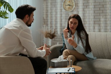 Günlük yaşam tarzı konsepti. Yaşlı bir kadın psikiyatrik tedavi görüyor, kadın psikoterapiste gidiyor, koltukta oturuyor, gergin bir ifade takınıyor. Psikolog sakinleştirici ilaçlar sunuyor..