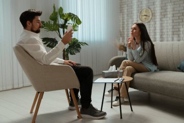 Günlük yaşam tarzı konsepti. Yaşlı bir kadın psikiyatrik tedavi görüyor, kadın psikoterapiste gidiyor, koltukta oturuyor, gergin bir ifade takınıyor. Psikolog sakinleştirici ilaçlar sunuyor..