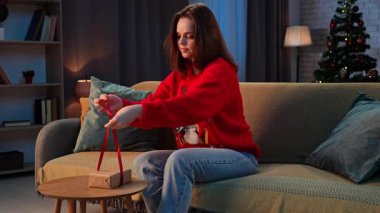 Çiftler tatillerini evde geçiriyorlar. Yeni yıl arifesini rahat bir evde kutlayan bir kadın, kanepeye oturup aile ya da arkadaş için hediye paketler, olumlu ifade. Yavaş çekim